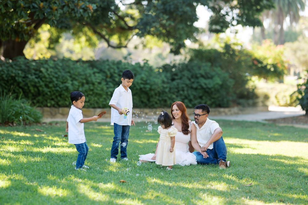 A loving family enjoys quality time together while playing and relaxing on green grass in a park setting.
