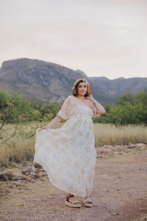 Ethereal white dress flowing in desert breeze with mountains and desert flora in background.