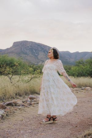 Expressive dance poses in flowing white dress set against desert mountain scenery.