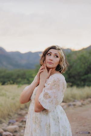 Dreamy portrait against desert mountains wearing a vintage-inspired white lace dress.