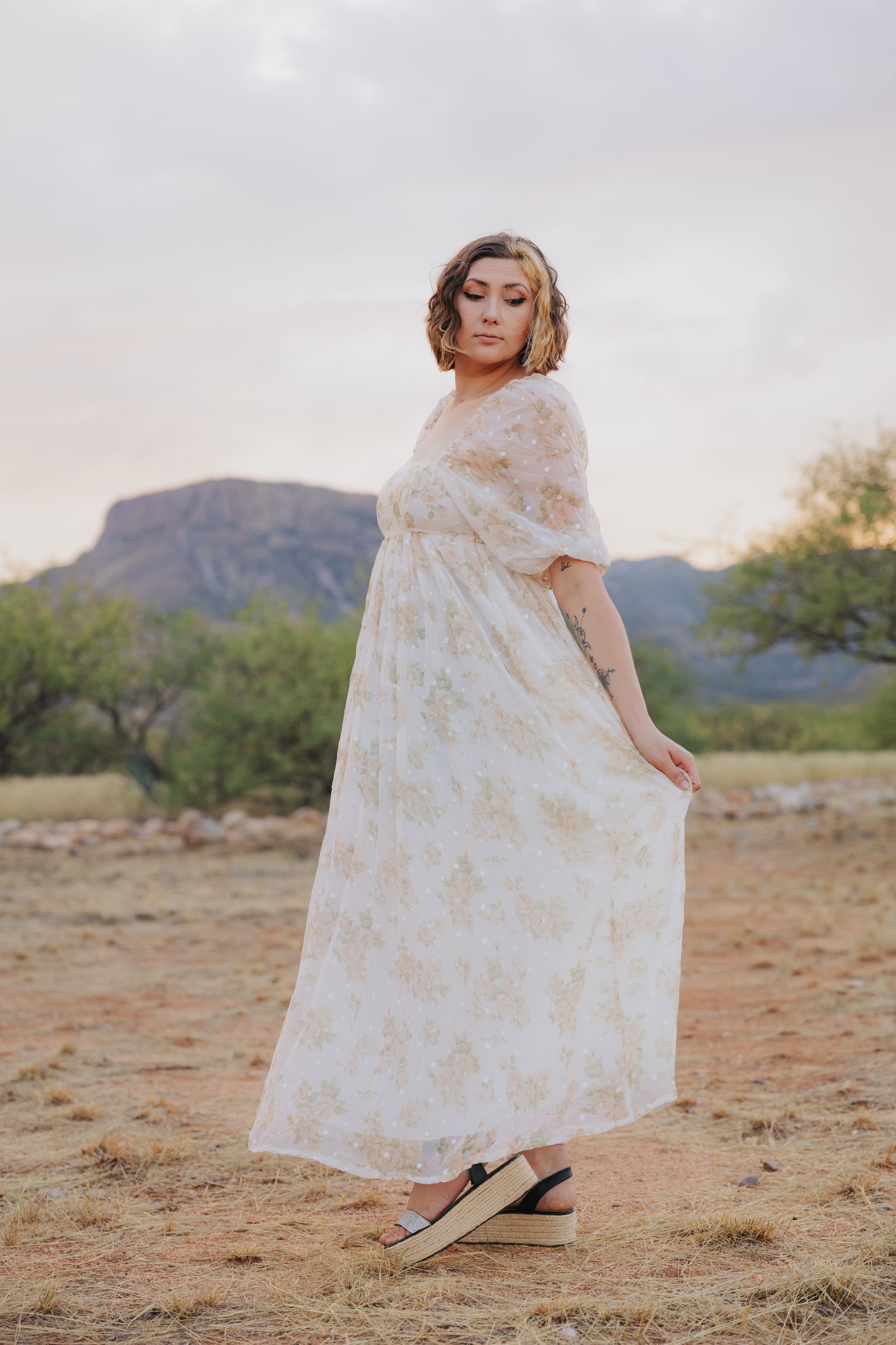A light floral dress moves gracefully in the desert wind with mountains in the background.