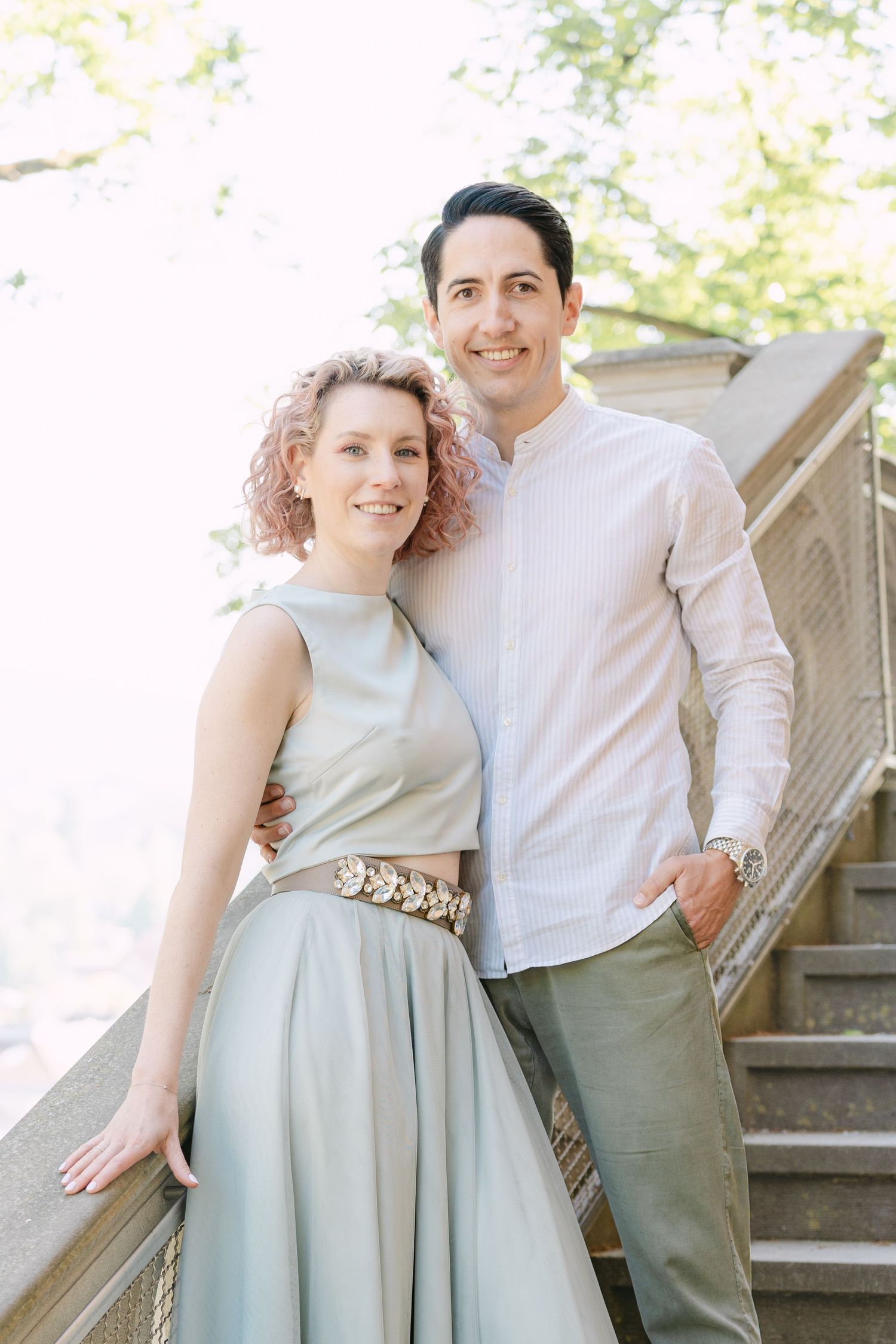 Stylish couple in coordinating pastel outfits posing on garden steps.