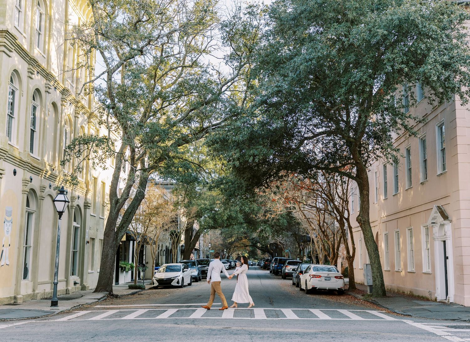A panoramic view of a tree-lined residential street with parked cars and crosswalks in an urban neighborhood.