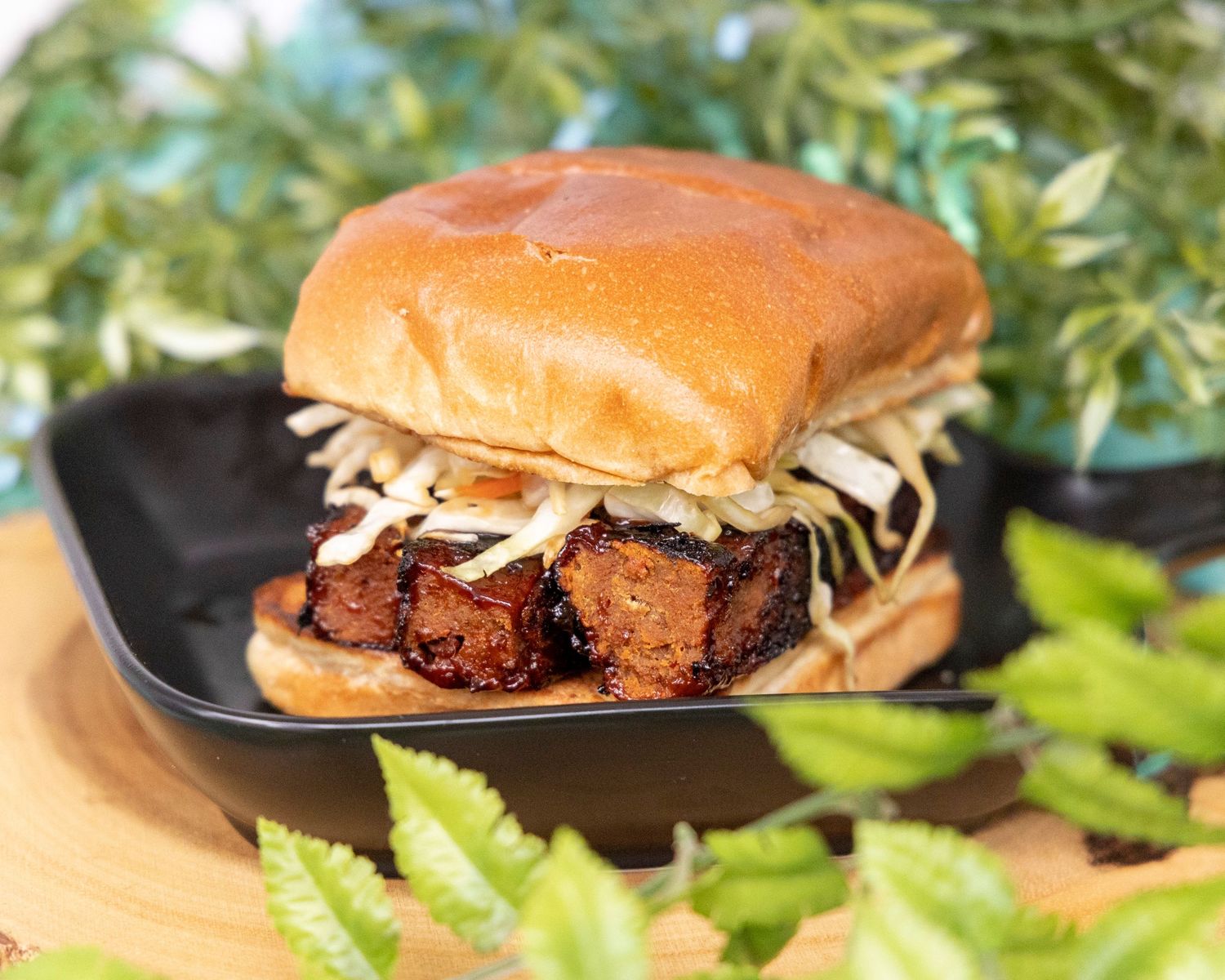 Multi-angle view of a juicy burger with melted cheese and caramelized onions on a soft bun against green foliage background.