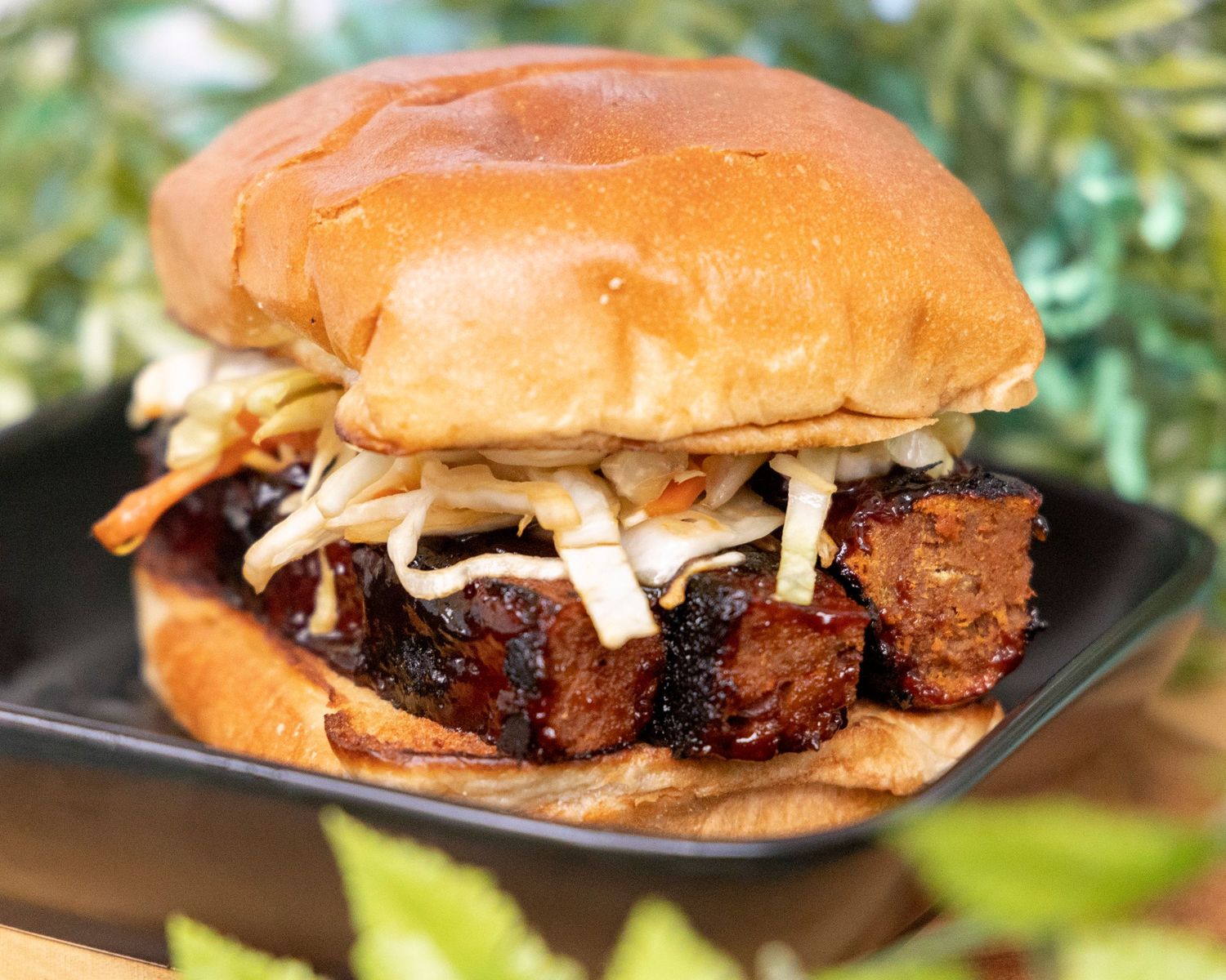 A close-up sequence showing the assembly of a juicy pulled pork sandwich with coleslaw on a brioche bun.