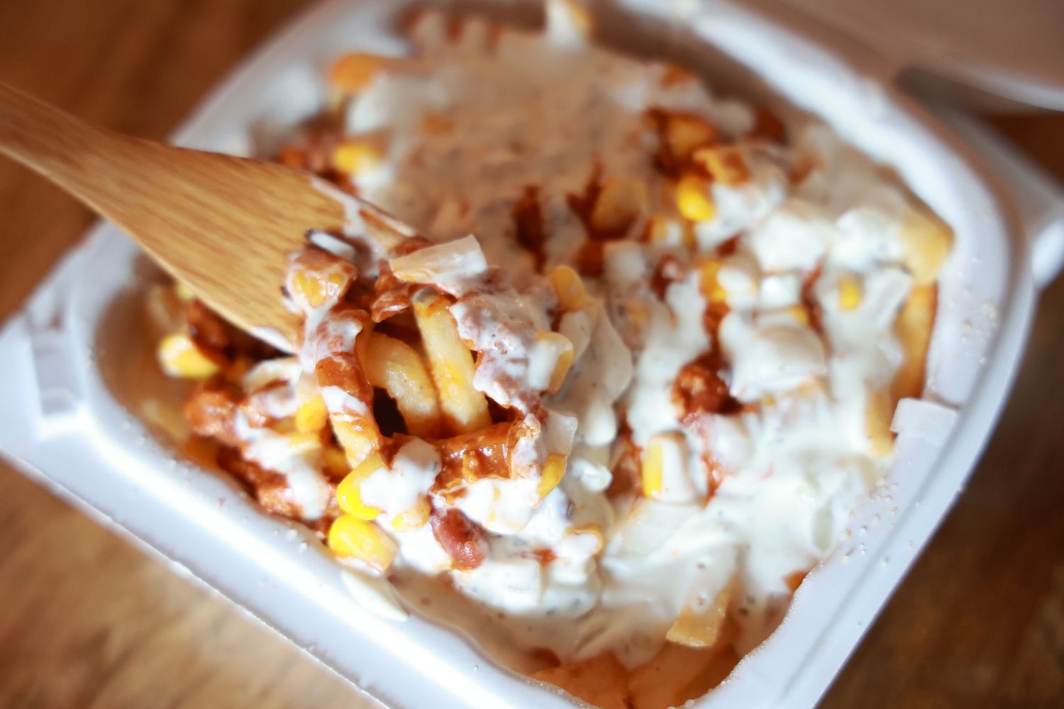 Several BBQ chicken sandwiches with melted cheese and corn are arranged on parchment paper on a wooden surface.