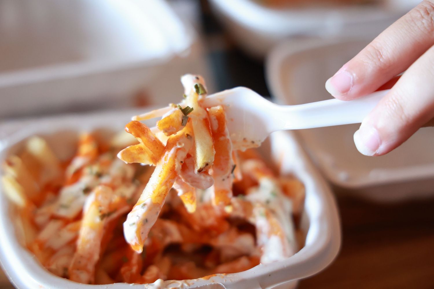 Chopsticks lifting spicy kimchi vegetables from a white ceramic bowl with sauce.