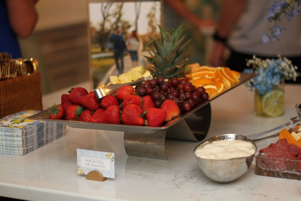 Fresh fruit and berries displayed on a buffet table with serving platters and bowls at an event setup.