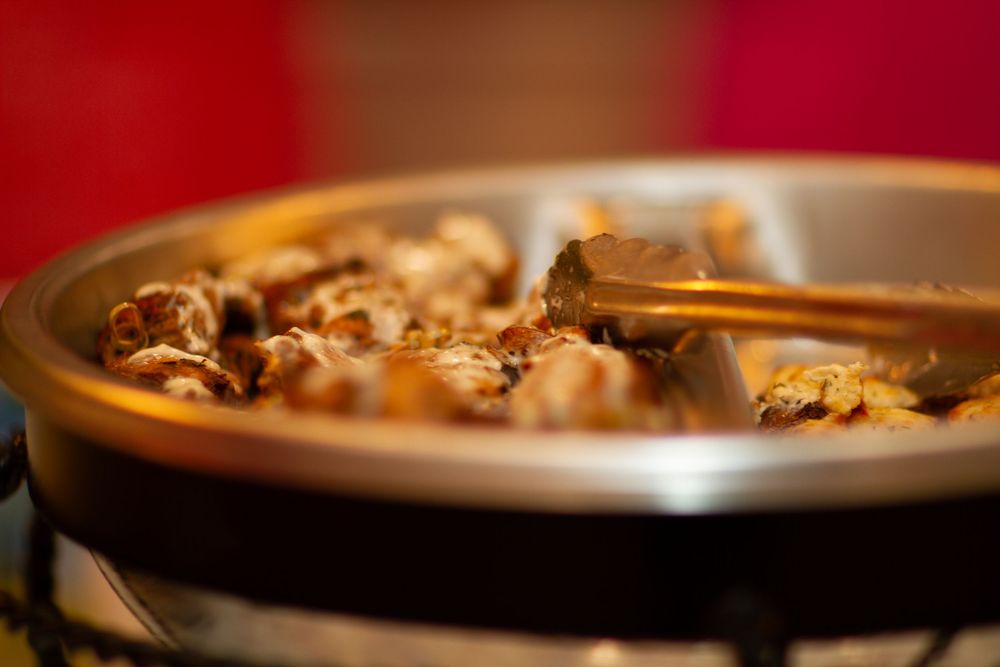 Shallow depth of field macro shot of cooking in a brown ceramic pan with warm lighting and rich tones.