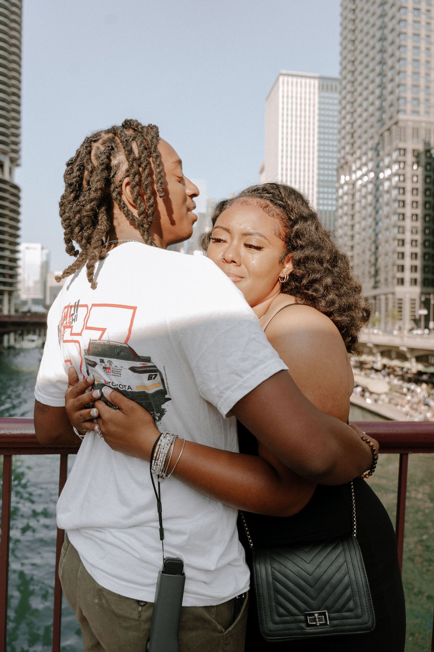 A montage of three photos showing people in white t-shirts embracing and hugging against a city backdrop.