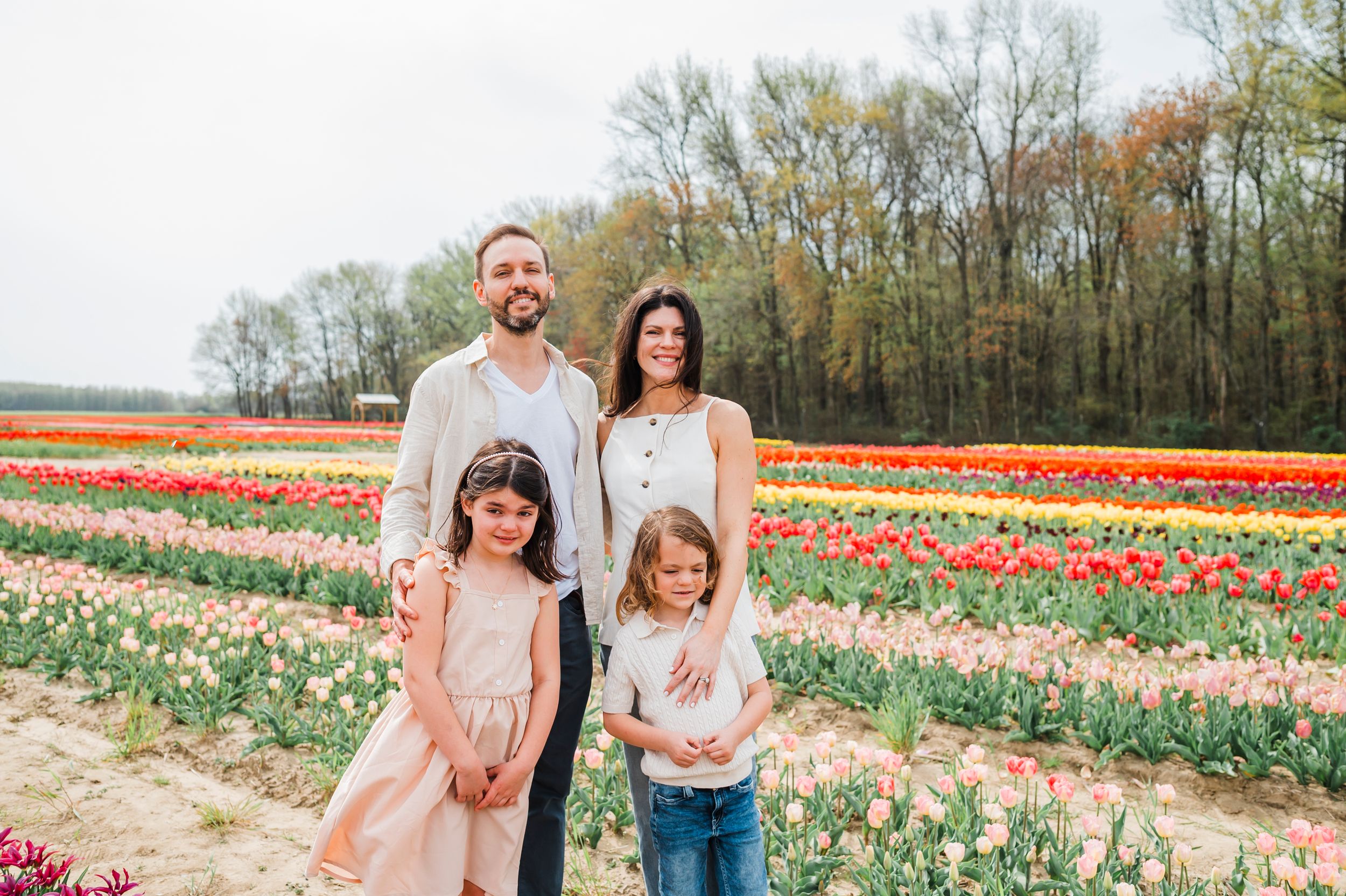 A group of people exploring colorful tulip fields in spring, surrounded by blooming flowers and trees.