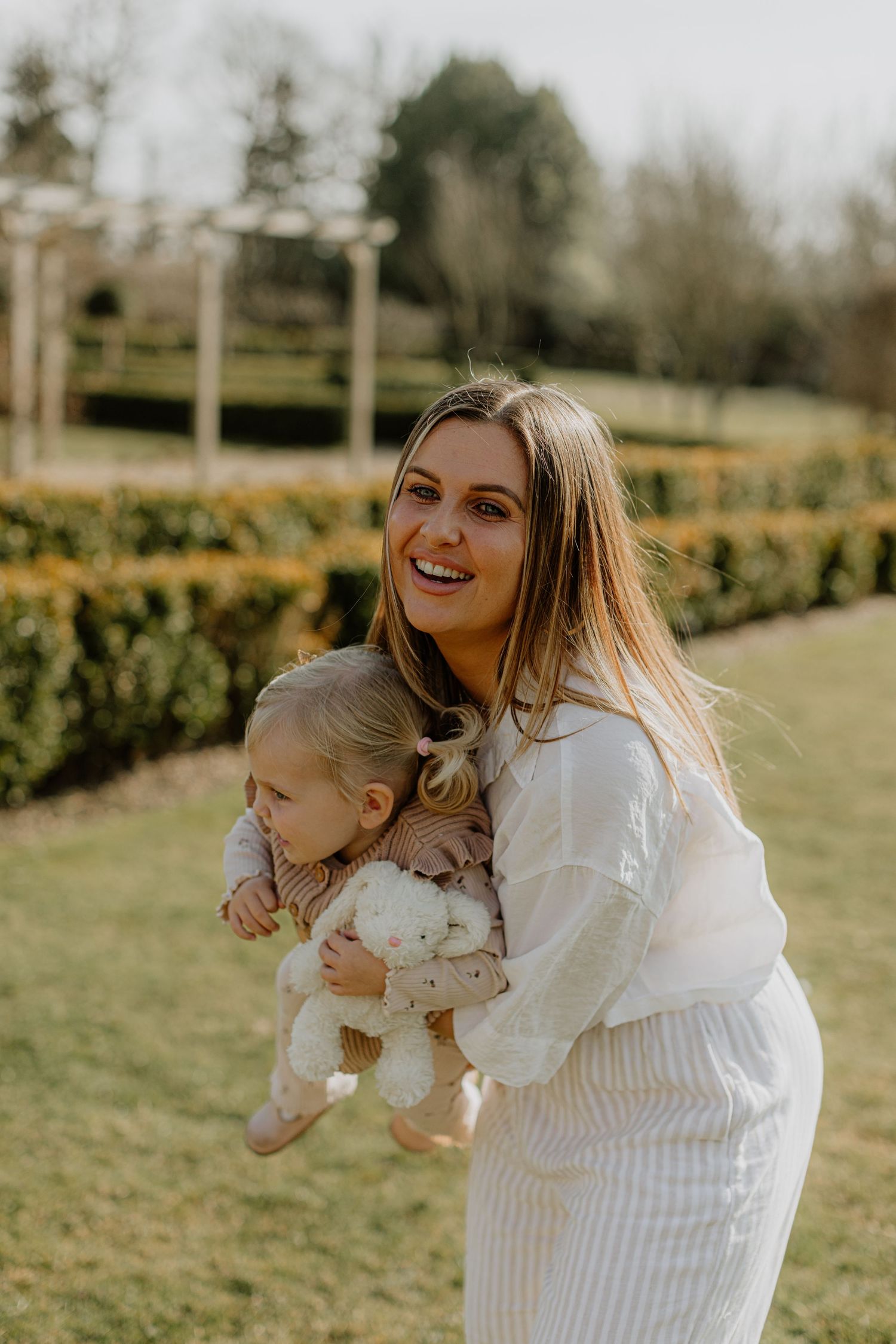 A playful moment captured in warm sunlight as two people share laughter in a garden.