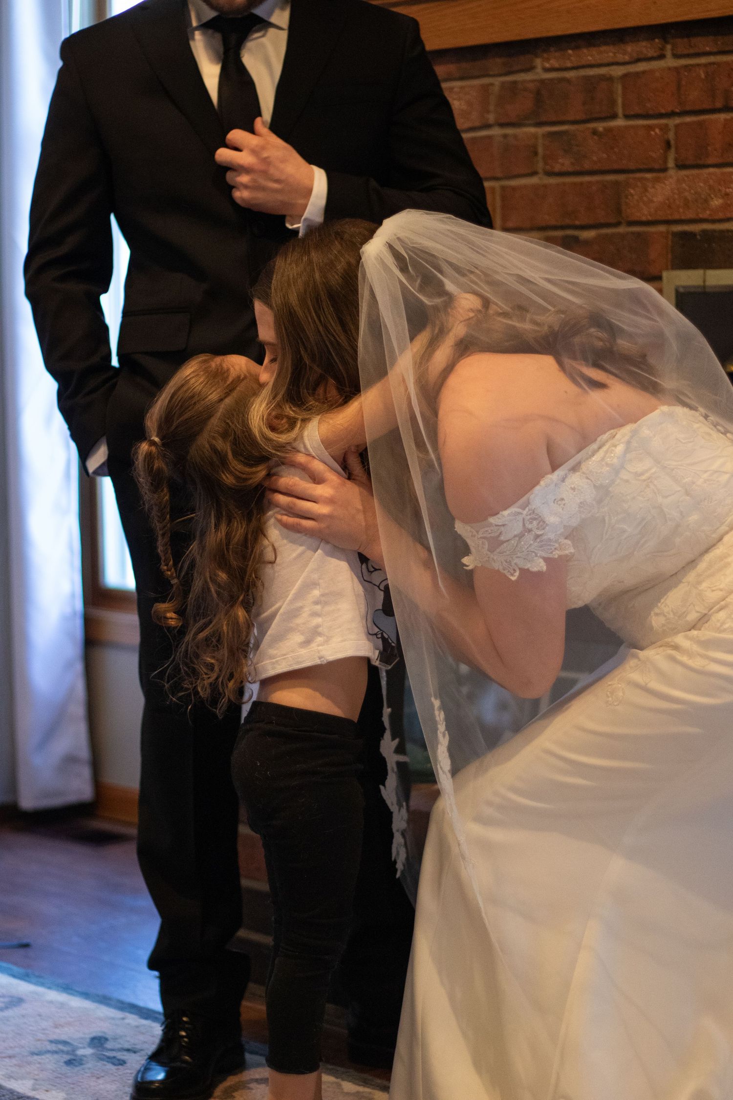 Bride leaning down to kiss nieces cheek as she stands at the alter with groom in the background