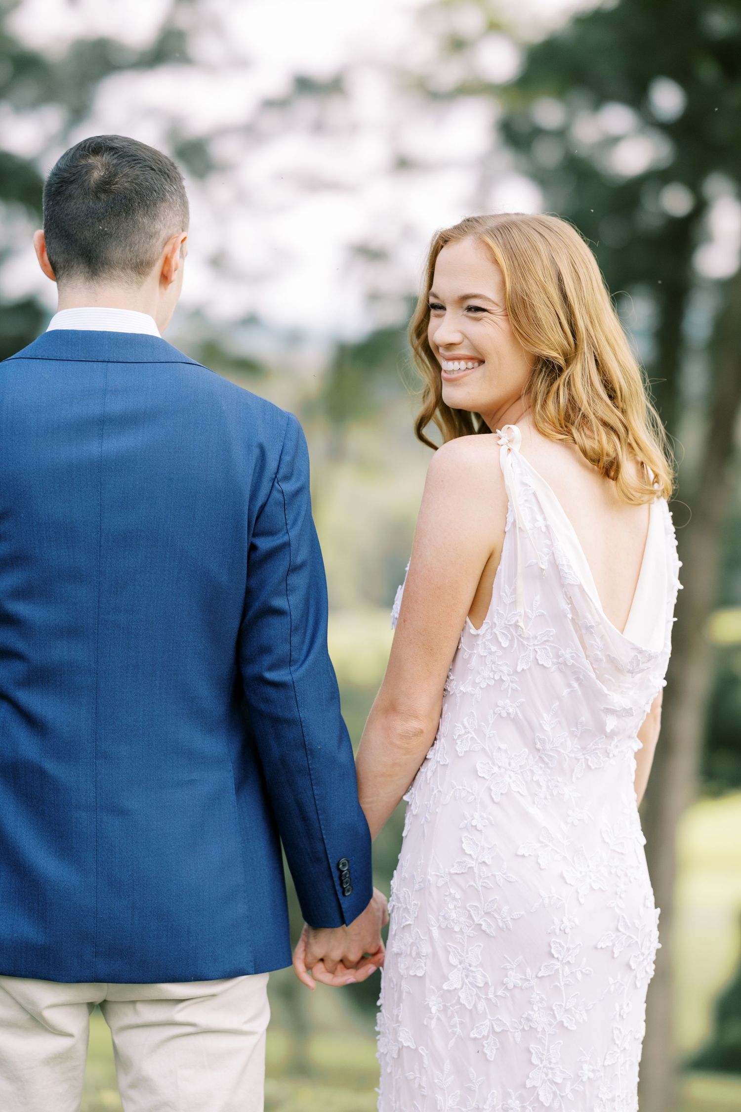 A couple holds hands while walking outdoors during an intimate wedding photo session in a natural setting at Pendry Natirar in Peapack, NJ.
