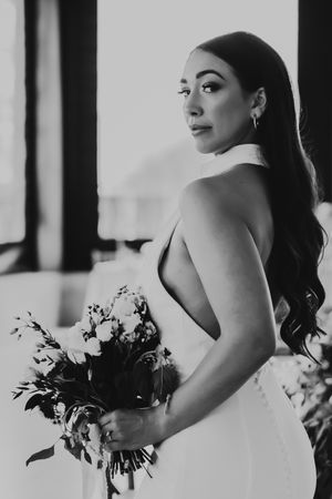 Black and white photo of bride carrying an elegant floral bouquet in a sleeveless wedding dress.