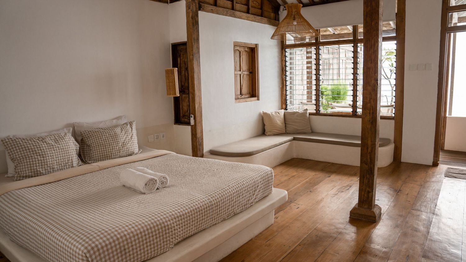 Minimal bedroom interior with wooden beams, white bedding and natural light.