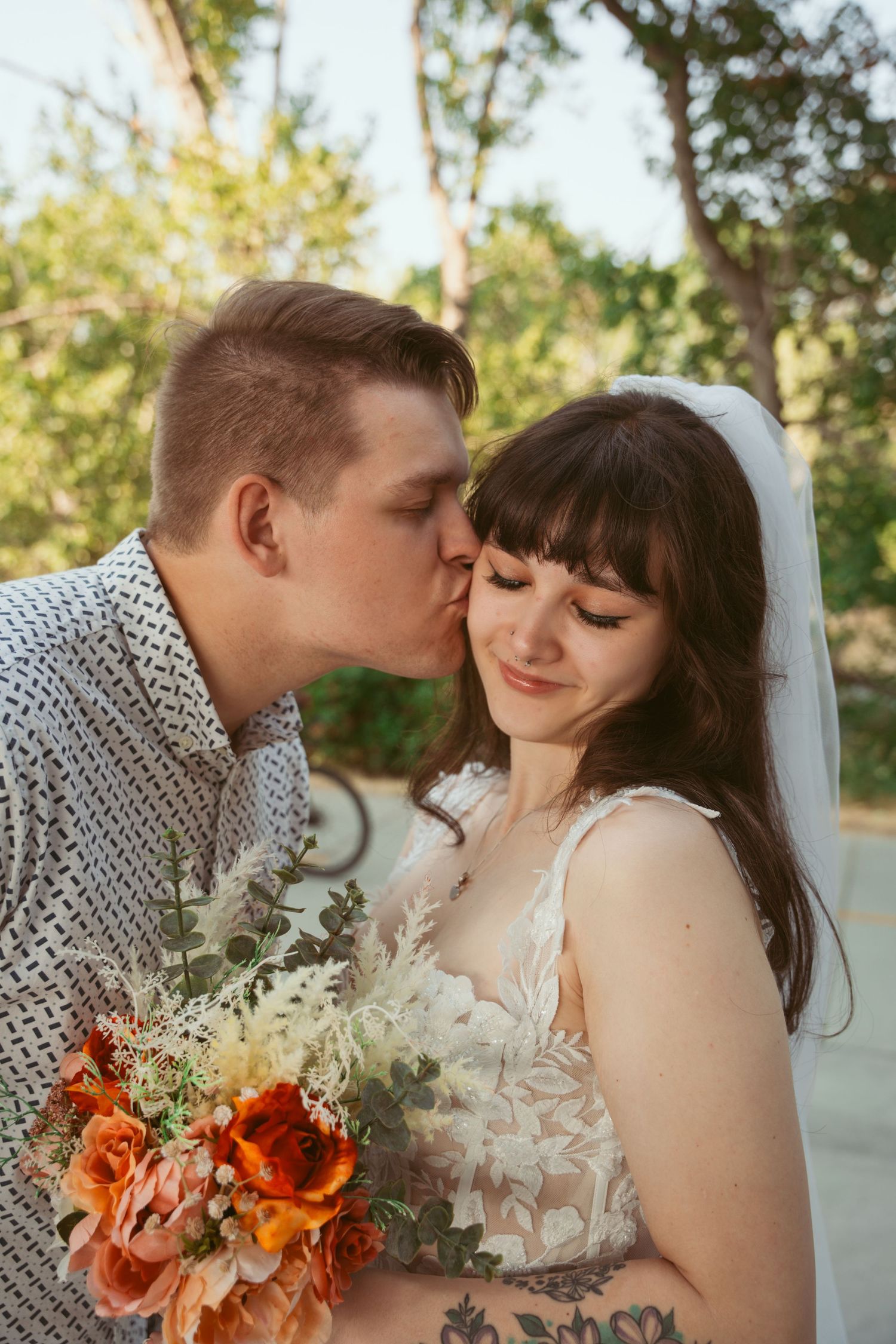 A tender wedding moment outdoors with autumn florals featuring orange and white flowers in a rustic bouquet.