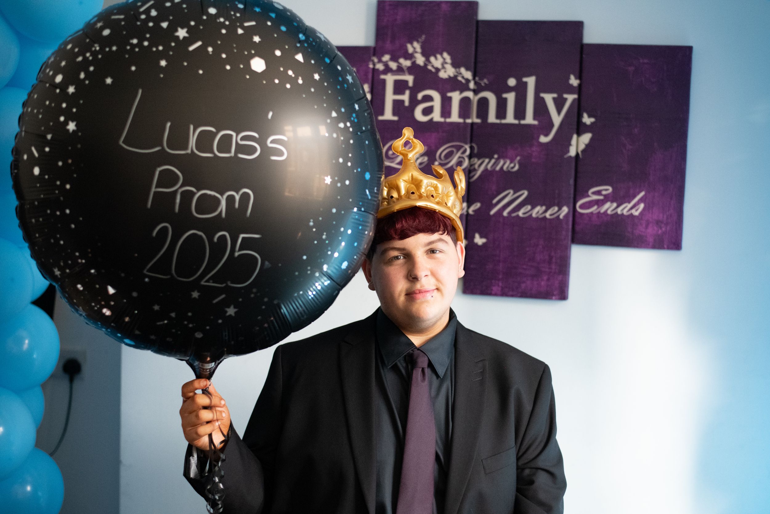 A large black balloon with starry design next to purple wall art reading "Family" in an indoor setting.