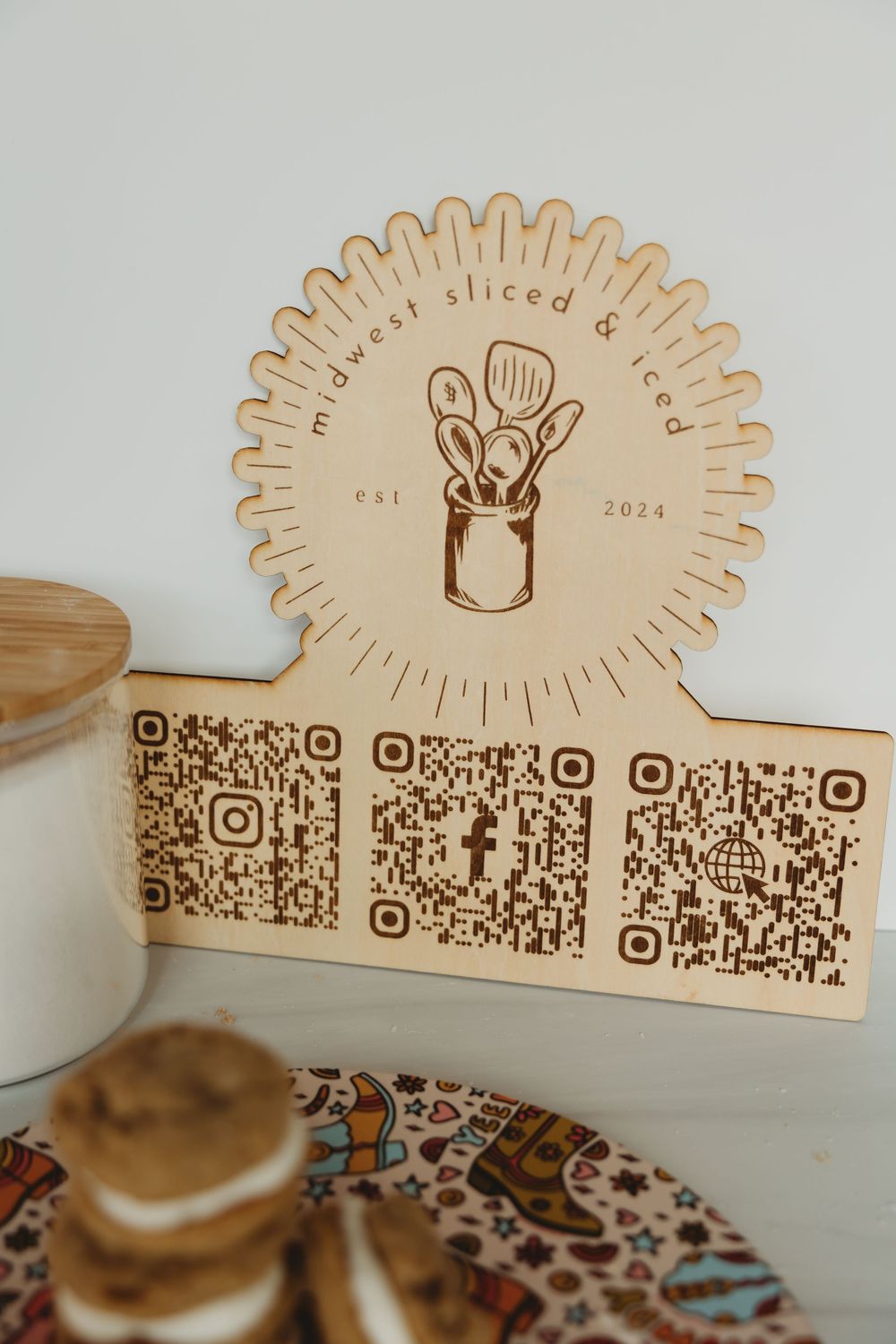 Wooden decorative display board with coffee cup design and QR codes engraved along the bottom edge.