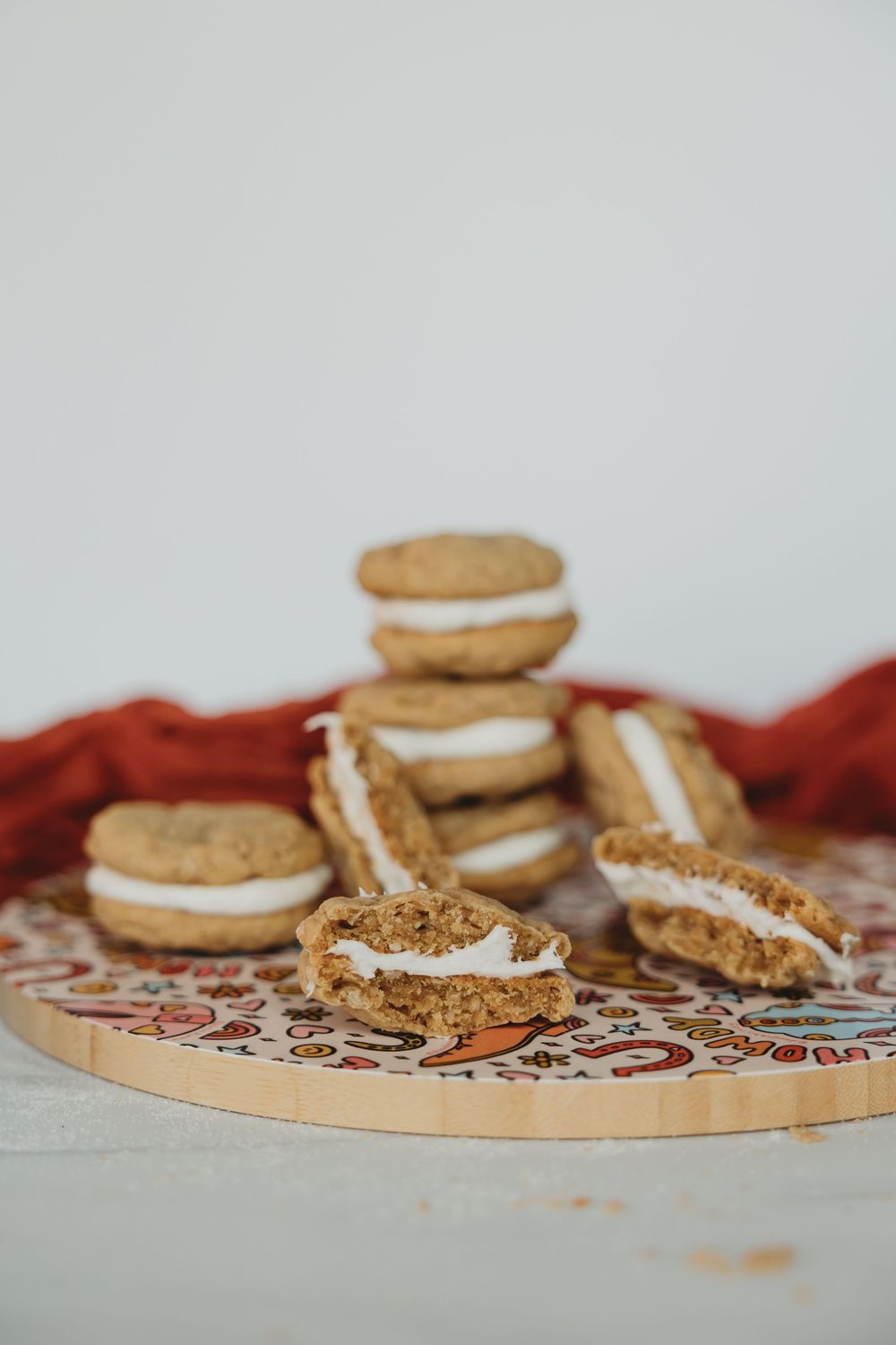 Side view of homemade cream-filled sandwich cookies displayed on a round serving plate with red fabric.