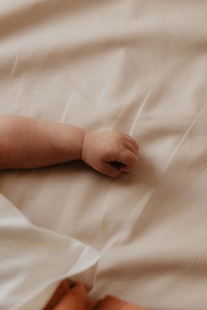 Delicate close-up series of tiny hands against soft white bedding.