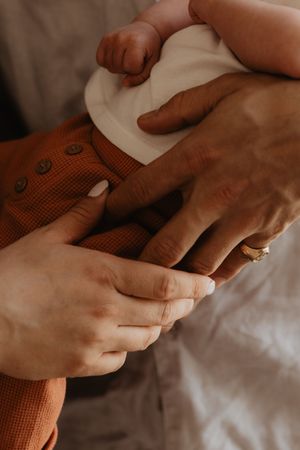 Intimate close-up of hands touching a rustic orange textile against white bedding.
