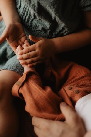 Gentle hands holding and examining a rust-colored knitted fabric in soft lighting.