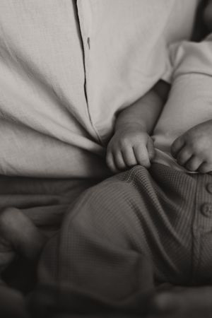 Close-up shot of tiny fingers grasping a gray textured surface in black and white.