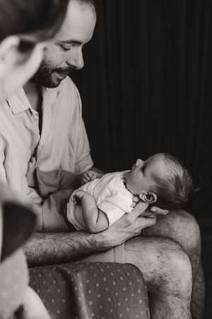 Tender black and white moment between parent and infant on a polka dot nursing pillow.