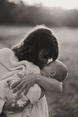 Black and white artistic photo of someone embracing a pillow outdoors.