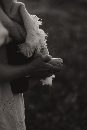 Monochrome image showing hands grasping delicate fabric in natural light.