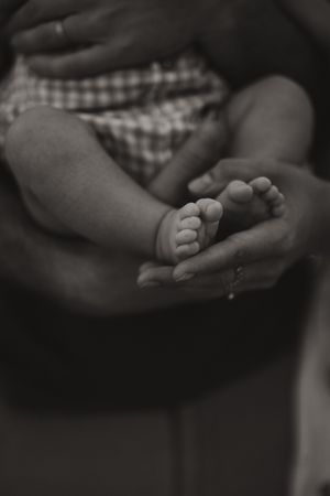 Close-up black and white series of tiny baby feet being held with care.