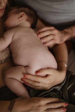 Intimate photo showing hands tenderly holding a sleeping infant in warm lighting.