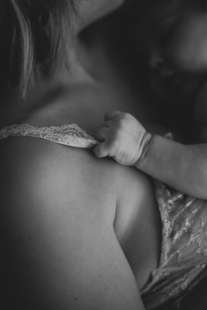 Artistic black and white capture of someone caressing a baby with delicate fingertips.