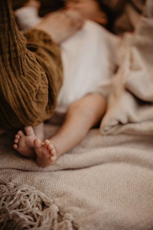 Close up detail of tiny baby feet on textured beige fabric.