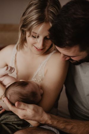 Intimate family portrait showing parents sharing a tender moment with their newborn.