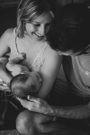 Loving moment captured in black and white as parents embrace their newborn baby.