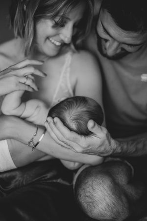 Black and white portrait capturing gentle embrace of parents with their sleeping baby.