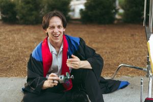 Student in graduation robe holds up diploma while sitting at a desk in series of celebratory photos.