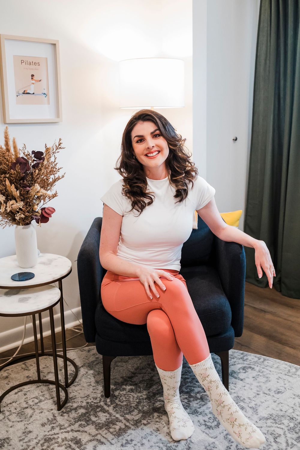 Lifestyle photo series showing casual outfit of white t-shirt, coral pants and cream ankle boots on patterned rug.