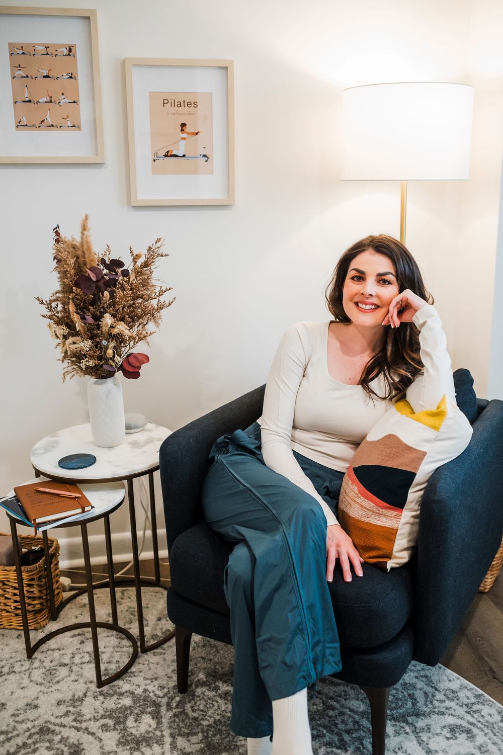 Person relaxing in a modern living room with dried flowers and framed artwork.