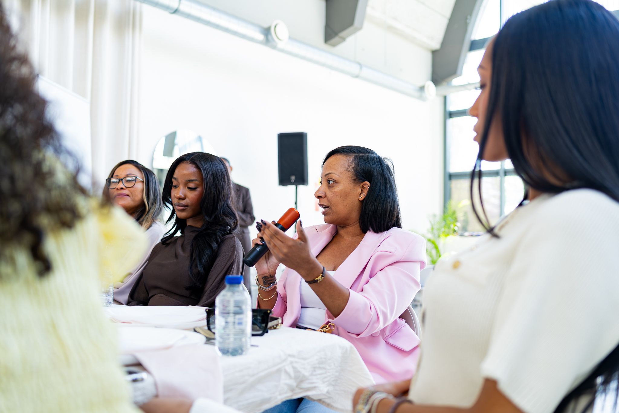 Group enjoying a social gathering in a bright indoor space wearing pink and white attire.