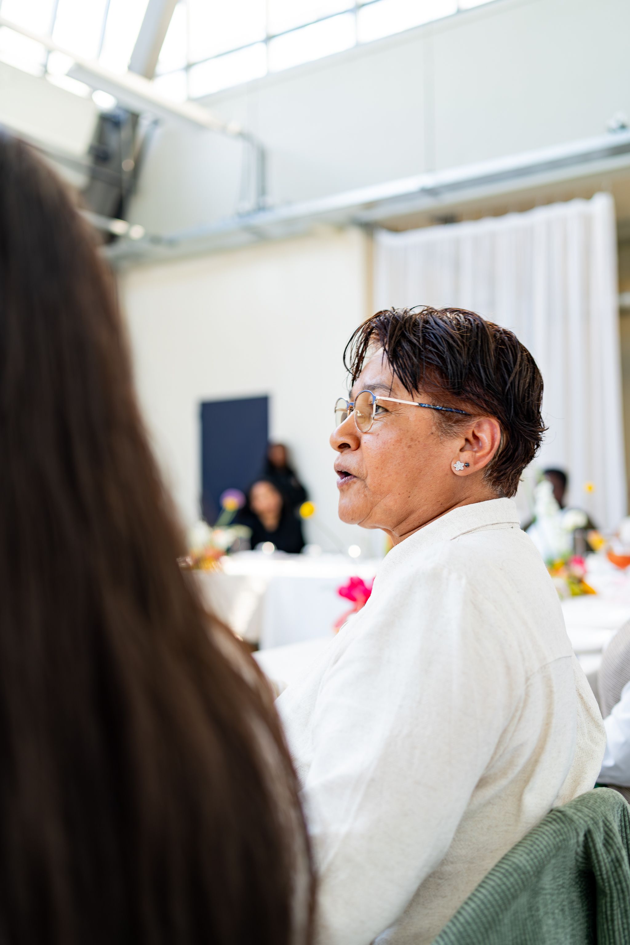 Side view of attendees seated during an indoor event in a light-filled space.