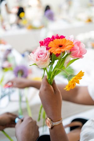 Colorful gerbera daisies and roses arranged in clear glass vases on a white table.
