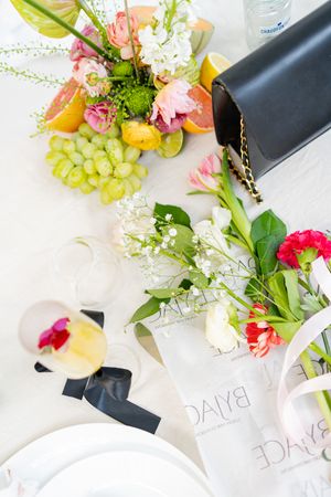 Fresh fruit and floral arrangements displayed on white place settings at an event.