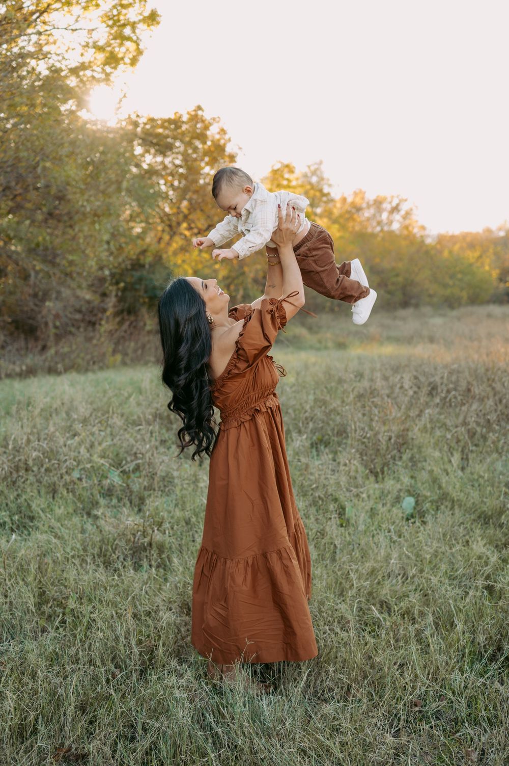 A figure in a brown vintage dress spins and twirls in a golden autumn field at sunset.