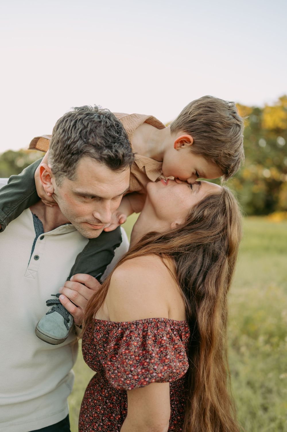 Romantic couple shares intimate moments in a sunny meadow while wearing casual attire.