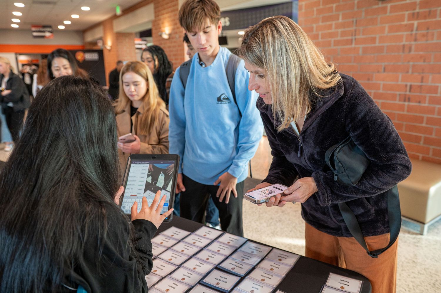 Attendees interacting at conference registration area with brick walls.