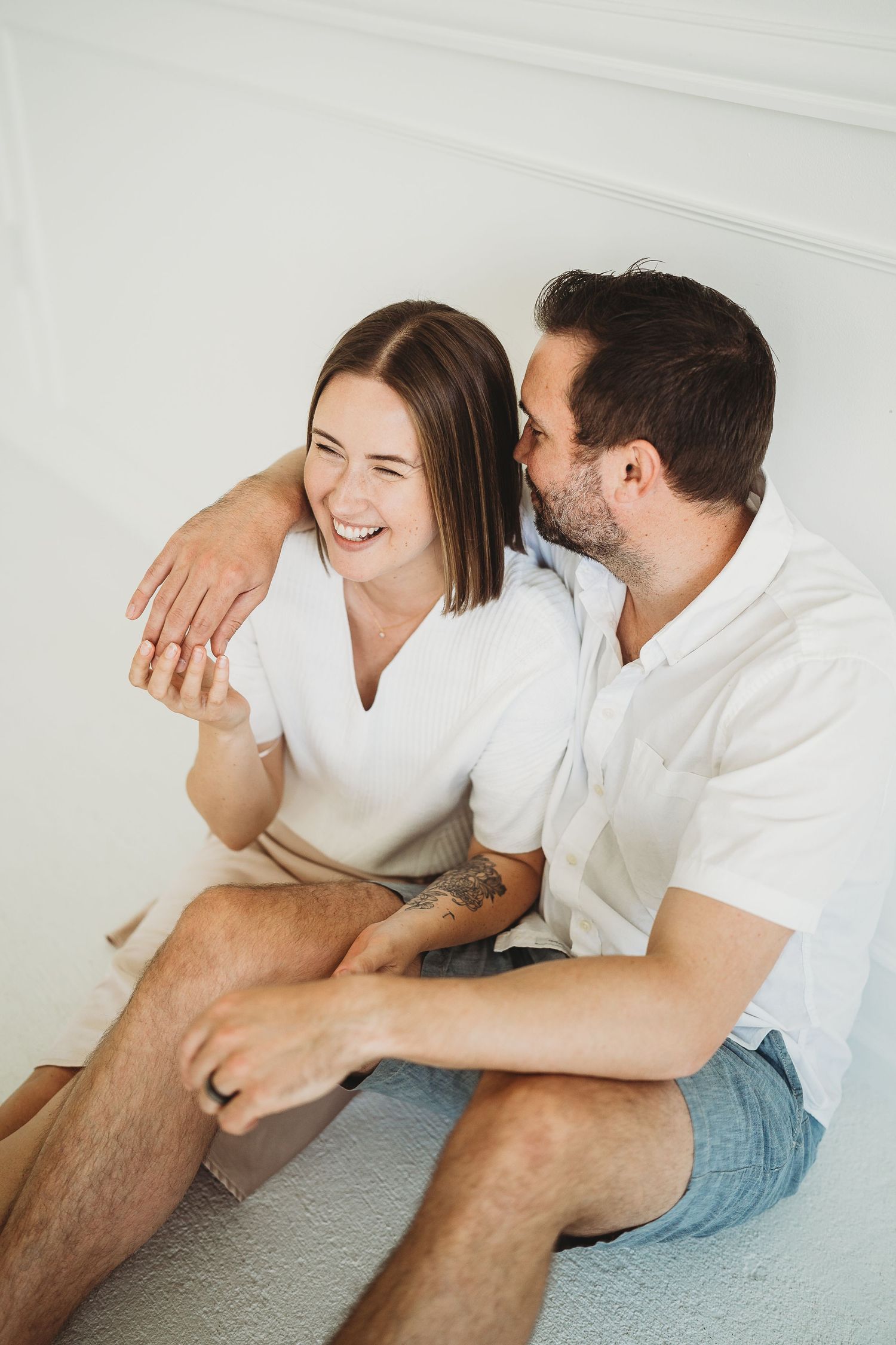 Intimate couple photoshoot in casual white outfits against a minimalist white background.