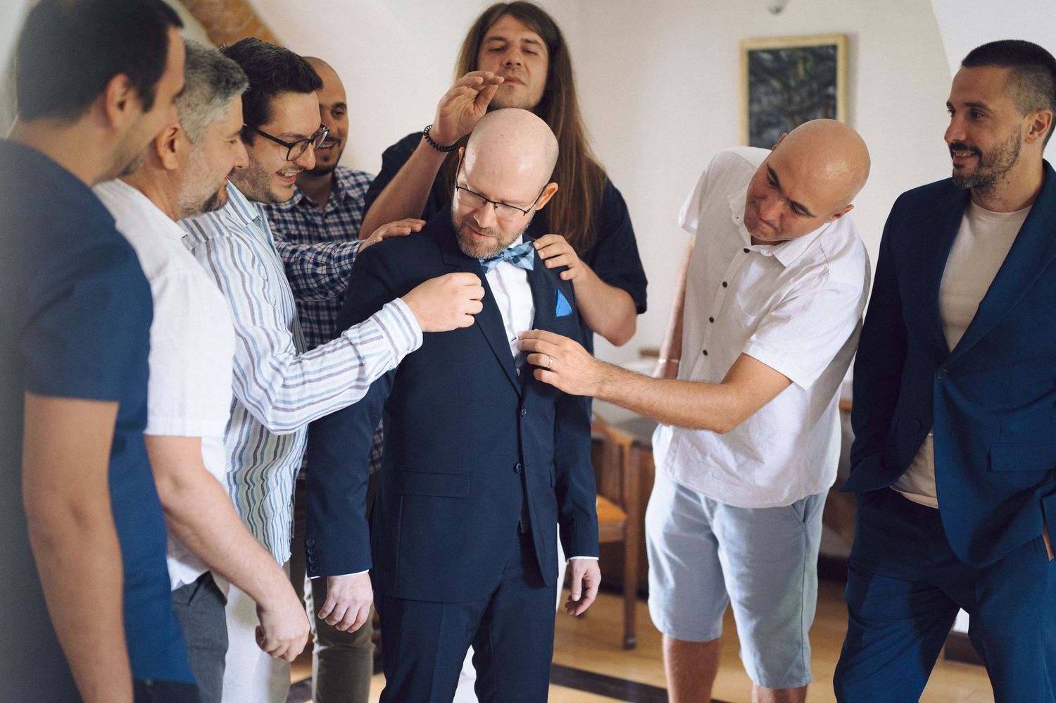 A line of people in business attire stand and talk while examining items together during a group activity.